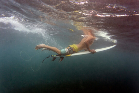 Low section of man surfboarding undersea