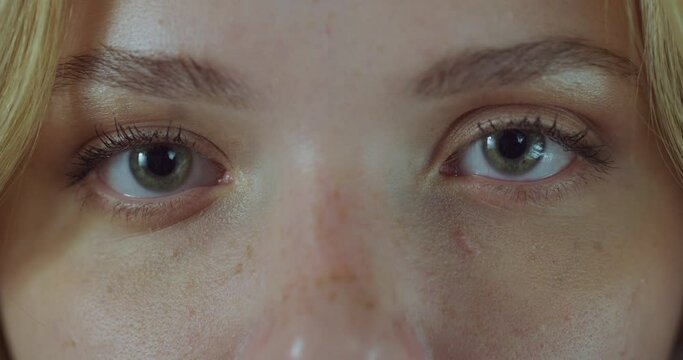 Close Up Macro Zoom Shot of an Eye. Young Beautiful Female Looking at the Camera, With Light Green and Brown Color Pigmentation on the Iris. Mascara is Applied to Eyelashes. Dilating Black Pupil.
