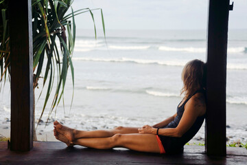 Side view of woman looking at view while sitting on floorboard by beach