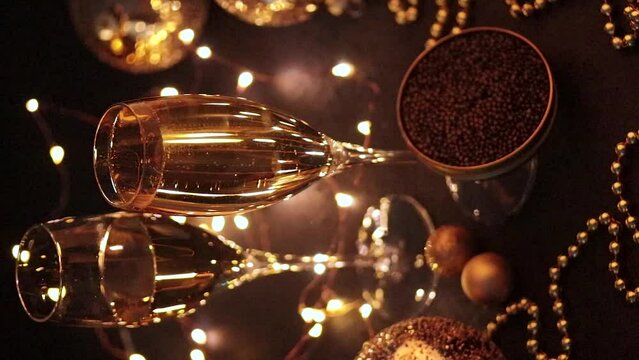 Black caviar in a mother-of-pearl spoon and glass of sparkling champagne with bokeh