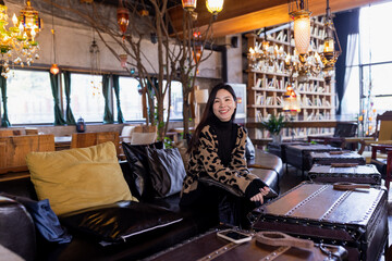 Fototapeta na wymiar Candid lifestyle portrait of Stylish Young Asian beautiful woman sitting in modern cafe at spring or autumn season.