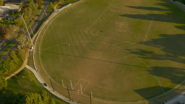 Multiple groups of people using empty sports field to enjoy the afternoon sun.