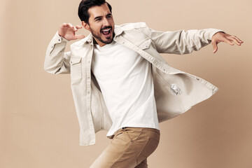 Stylish man smile runs and jumps on a beige background in a white t-shirt and business jacket,...
