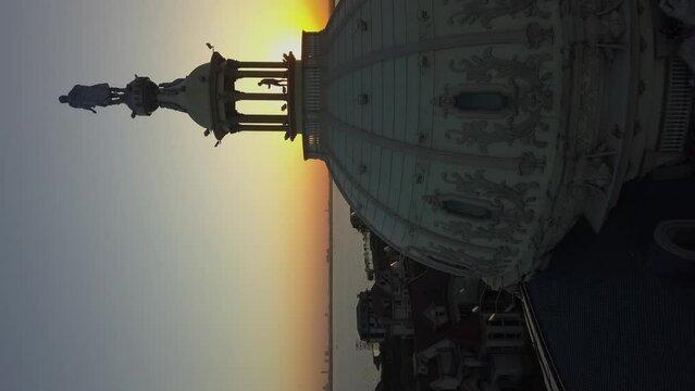 Vertical format: Sunset aerial flies past ornate dome atop building
