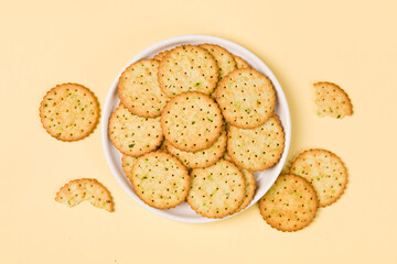 round crispy biscuits in plate on yellow background.