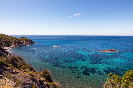 High angle view over Ogliera beach, a little wild free beach with dark sand, rocks and stones near Pomonte