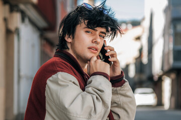 young man with pensive gesture with phone in the street