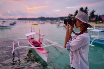 Photography and travel. Young woman in hat holding camera  with beautiful tropical sea view.