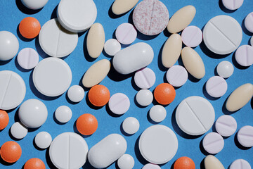 Medicine and drug concept. Pharmacy and health care background. Bunch of different tablets and pills on blue.