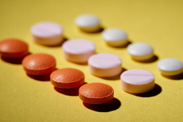 Pharmacy health care concept. Drugs illustration. Close up of different tablets and pills rows. on yellow background.