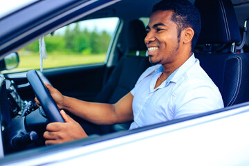 latin man in white t-shirt at the wheel of his new car outdoor summer day