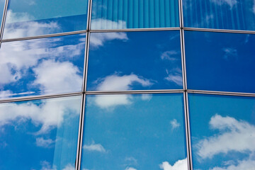 windows of a modern building with sky and clouds reflected into it