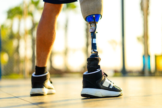 person with a physical disability and prosthetic leg walking at the beach outdoors at sunset