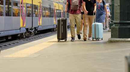 People and tourists walk with suitcases in the train station..Tourists ready to get on the train to leave and tourists who have arrived at their destination.
