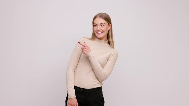 Portrait of beautiful blonde woman pointing to the left side, smiling surprised presenting something at copyspace, natural and casual. Isolated on white background. 