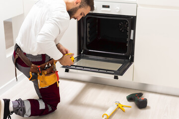 Man Repairing Domestic Oven In Kitchen