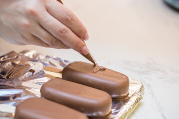woman confectioner decorates marshmallows in chocolate on a stick. home bakery concept.