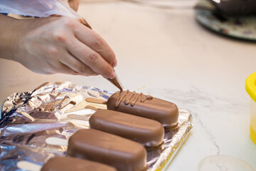 woman confectioner decorates marshmallows in chocolate on a stick. home bakery concept.