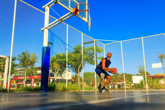 man with leg prosthesis playing basketball in tropical sea side at sumset time