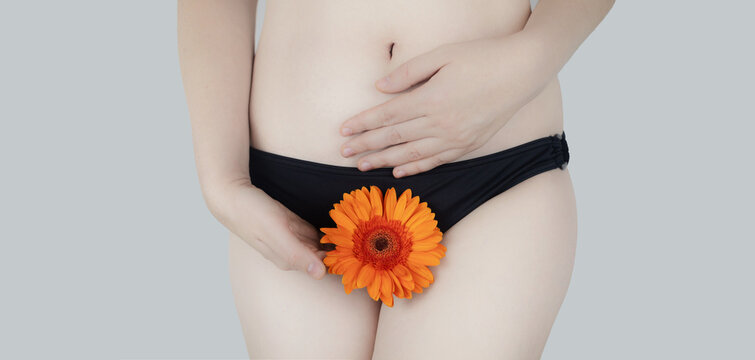 Virginity. Menstruation. Critical days. Concept photo. The girl holds a flower in the crotch area, symbolizing the hymen, critical days and gynecological problems.
