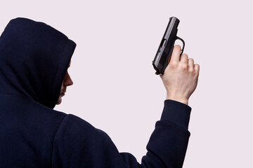 man wearing hoodie points a gun, rear view isolated in white, mysterious man holding gun