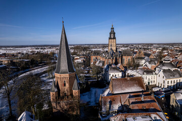 Cinematic aerial of Drogenapstoren in medieval Hanseatic Dutch tower town Zutphen in the Netherlands with historic heritage buildings covered in snow in the background