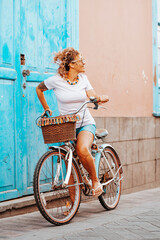 Young adult female enjoy riding bike alone in the street. Blue door house in background. Woman...