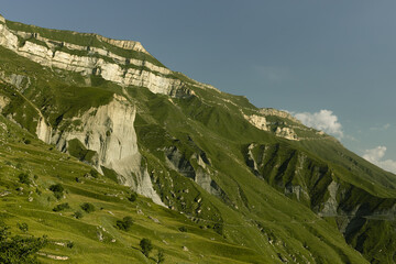 Amazing summer mountain landscape - folded mountain slope with grey layered rocky scree, cliffs...