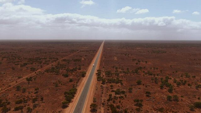 Aerial drone panning shot of a campervan on empty road in the Outback. Nullarbor in South Australia.