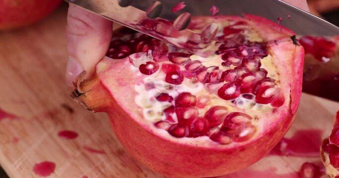 Cut juicy ripe red pomegranate , cut with a sharp knife of ripe pomegranate during cooking