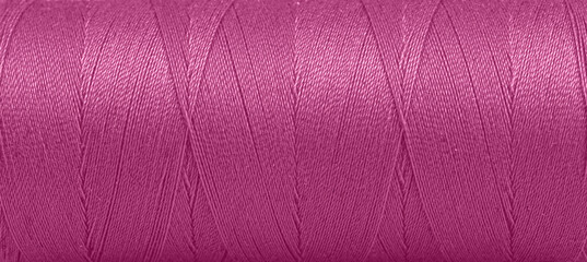 Texture of threads in a spool of pink color on a white background