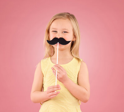 Girl, Child And Portrait In Studio With Moustache Prop On A Pink Background With A Smile And Stick. Female Kid Model With Happiness, Creativity And Comic Icon In Hand Isolated On A Color And Space