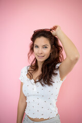 pretty young woman with black sunglasses and long hair with flowered shirt is standing in front of pink background