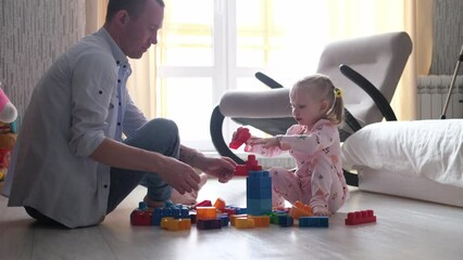 Dad and daughter are building family home. Happy family. Educational games for children. Father and daughter play colorful cubes in the children's room. Teaching child through play activities.