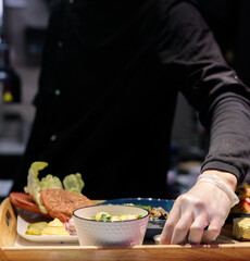 The cook in gloves collects lunch on a tray. Food court, cafeteria in the business center.