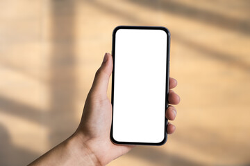 Hand holding white mobile phone with blank white screen in blur shadow background.