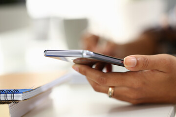 Student writes in notebook and holds smartphone