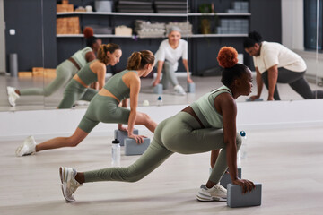 Fototapeta na wymiar Group of women exercising together with instructor during sport training in gym