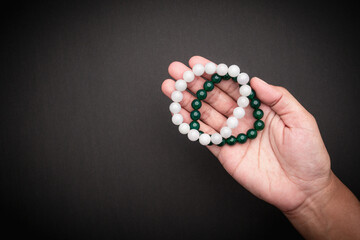 Jade bangles or bracelets in hand against a black background