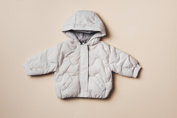Fashion baby hooded puffer jacket on beige background. Top view, flat lay. Newborn clothes outfit....