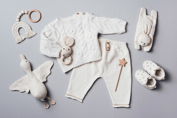 Obraz na płótnie Canvas Set of baby stuff and accessories for newborn on brown background. Baby shower or baby care concept. Flat lay, top view. Knitted sweater, pants, shoes, bib, wooden toys and soft bird.