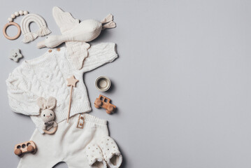 Set of baby stuff and accessories for newborn on brown background. Baby shower or baby care concept. Flat lay, top view. Knitted sweater, pants, shoes, bib, wooden toys and soft bird.
