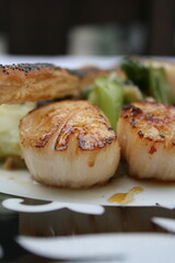 Coquille Saint-Jaques justes colorées présentées sur une assiette noire et blanche