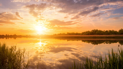 Fototapeta na wymiar Scenic view of beautiful sunset or sunrise above the pond or lake at spring or early summer evening.