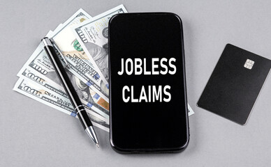 Credit card and text JOBLES CLAIMS on smartphone with dollars and pen. Business concept