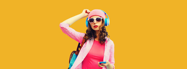 Summer colorful portrait of stylish modern young woman listening to music in headphones with...