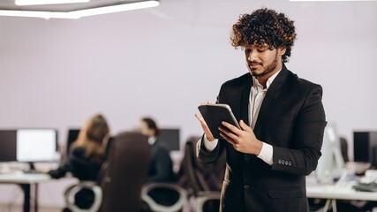 Handsome businessman using tablet. Indoor shot of focused office manager with digital device