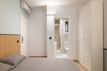 Double bed with gray linen, built-in wardrobe and air conditioning overlooking compact shower room....