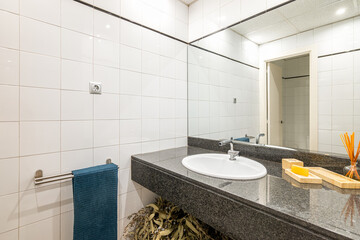 Mirror view in spacious bathroom with large stone countertop mirror and a sink with reflective...