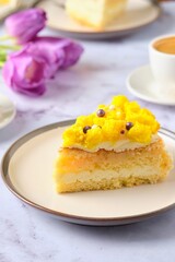 Sliced biscuit cake with cream cheese cream, lemon layer and yellow biscuit decor on a ceramic plate on a light background. Recipes for biscuit cakes.